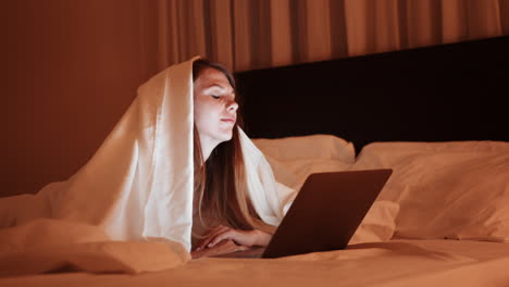 woman working on laptop in bed at night