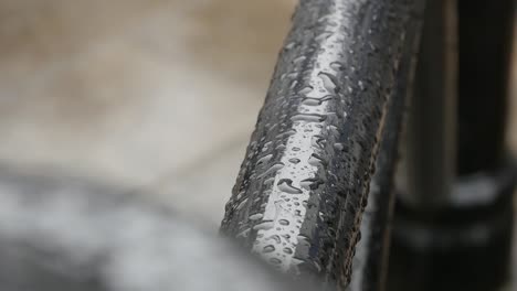 a handheld shot focusing on the water on this black pole from the rain