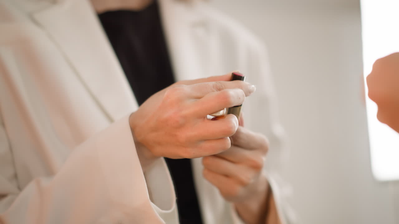 mujer elegante abre lápiz labial rojo girando el tubo para pintar los labios