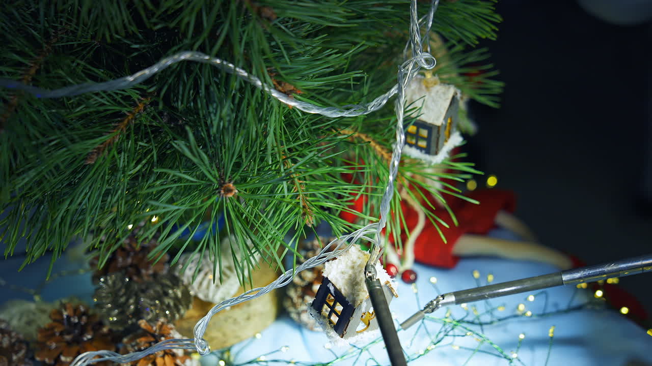 Christmas tree is decorated by robotic tools. Metal robotic arms decorating fir tree in New year. Innovations in technology. Close-up.