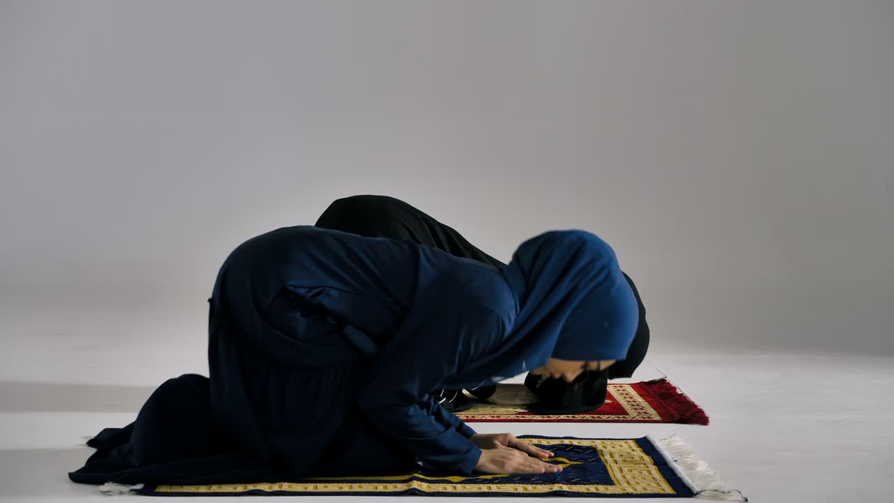 전통적인 히자브를 입은 두 명의 아시아 무슬림 젊은 여성들이 모스크에서 하나님을 찬양하고 이슬람 신앙을 실천하고 있습니다.