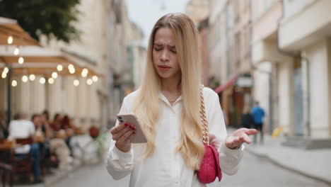 surprised young woman use smartphone loses bad news fortune loss fail outdoors in city street