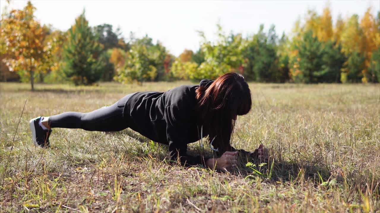 Woman doing a plank exercise in an autumn park