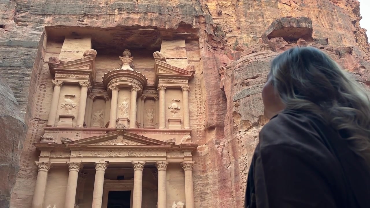 Immagini mozzafiato di una donna che ammira con stupore la magnifica facciata del Tesoro a Petra, catturando un momento intimo e indimenticabile in uno dei monumenti antichi più iconici del mondo, Giordania.