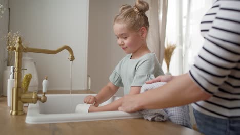 side view video of little girl helping wash the dishes