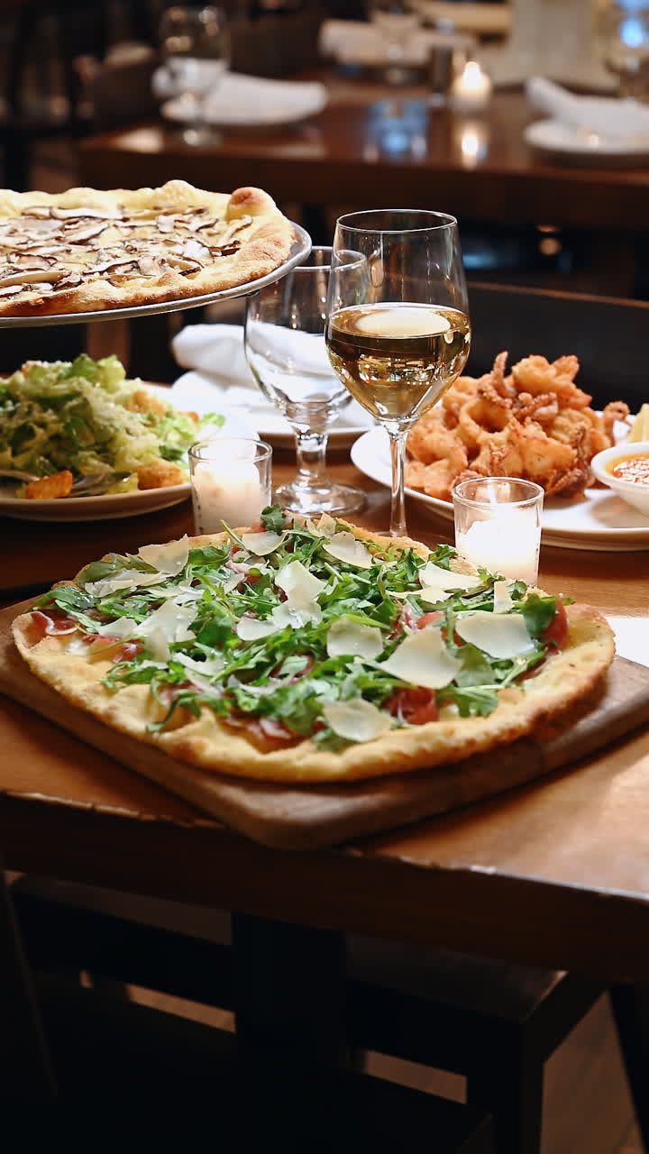 Deliciosa cena con pizza, ensalada y gambas en un restaurante acogedor. Una mesa está puesta con pizza, ensalada, gambas y bebidas en un restaurante por la noche.