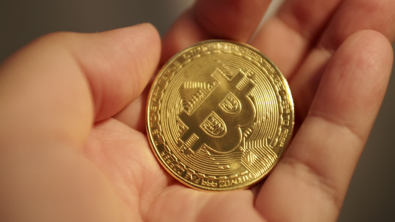 volviendo usando sus dedos, un individuo se aferra a una pieza de oro bitcoin
