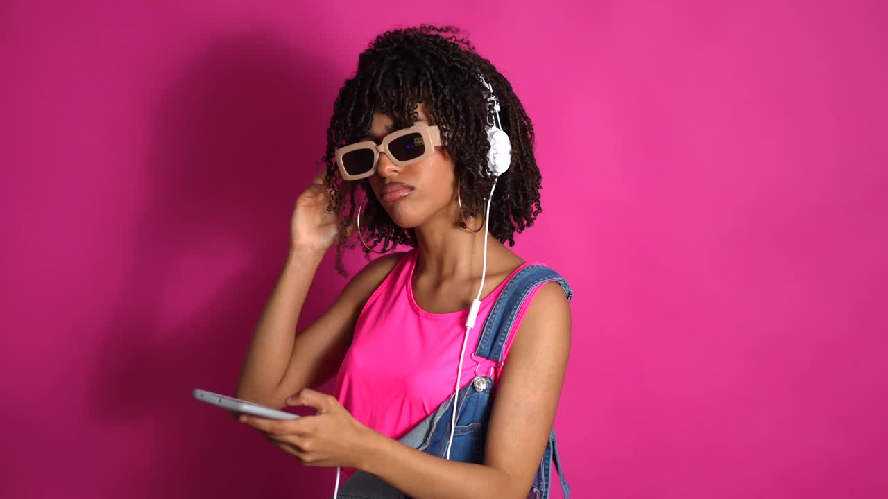 Woman with headphones and sunglasses listening to music on smartphone