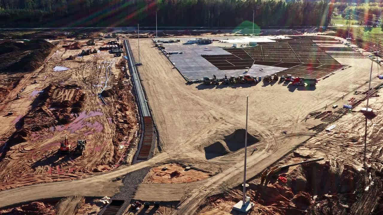 Large construction site with leveled area, materials, equipment, and lighting poles