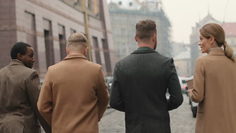 rear view of multiethnic business team talking and walking on the street in autumn