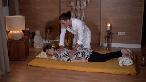 spiritual therapist massaging back of relaxed woman