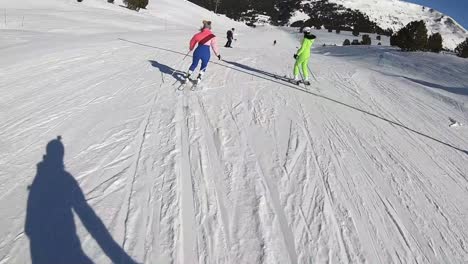 skiers in colorful ski suits going down a slope at a ski resort in the alps