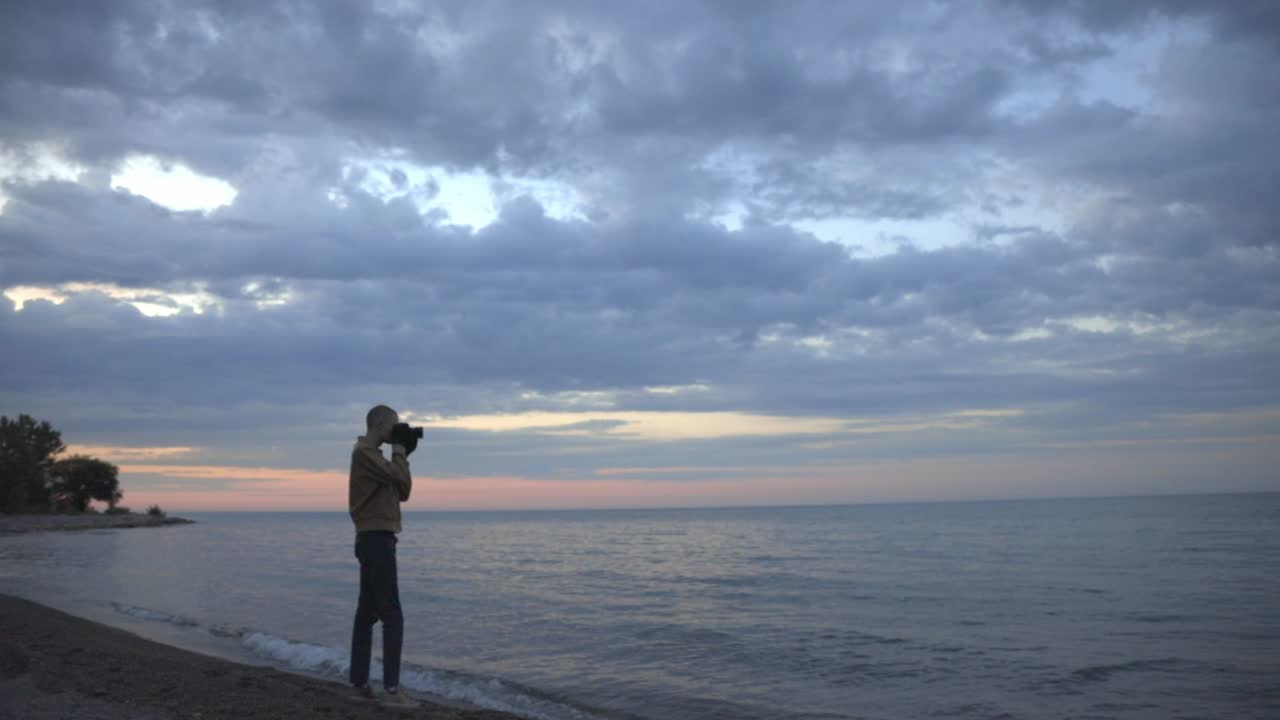 Man Taking Photos Of A Peaceful Scene Of The Ocean And Horizon On An Early Evening - wide shot