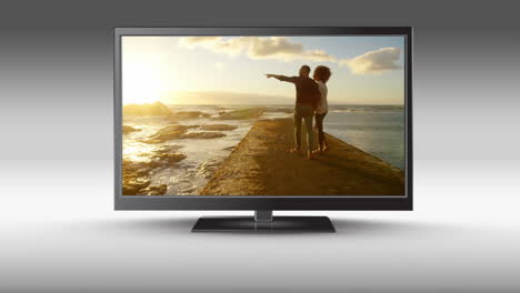 flat screen tv with a couple at the beach on its screen