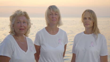 three women with pink breast cancer awareness ribbons