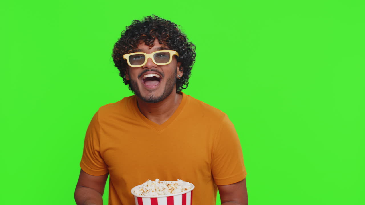 Excited indian man eating popcorn and watching interesting tv serial sport game film online movie