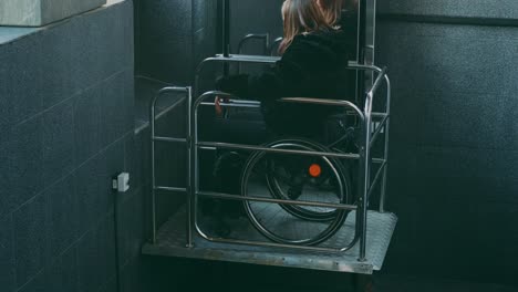 woman with disabilities in a wheelchair climbs stairs on a mechanical lift.