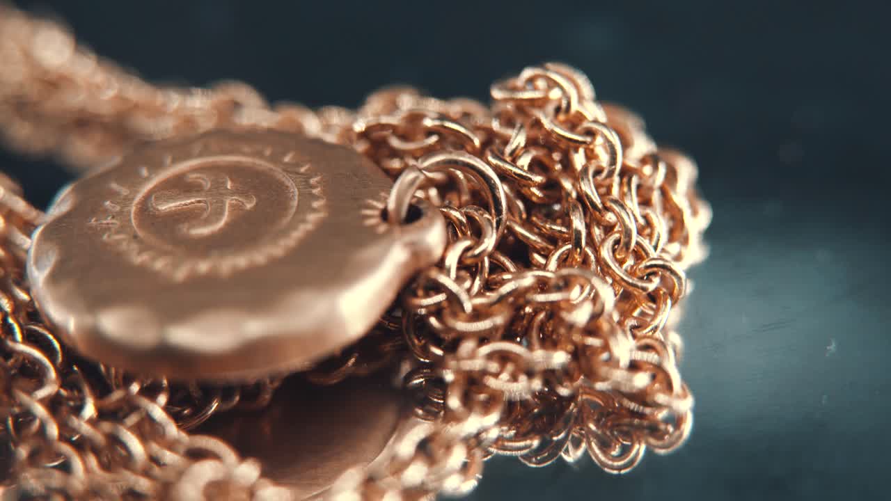 황금 메달리온 목걸이의 상세한 매크로 클로즈업  ⁇ , 태양 기호의 중간에 날아다니는 새, 회전하는 스탠드, 거울 반사, 스튜디오 조명, 4k 비디오