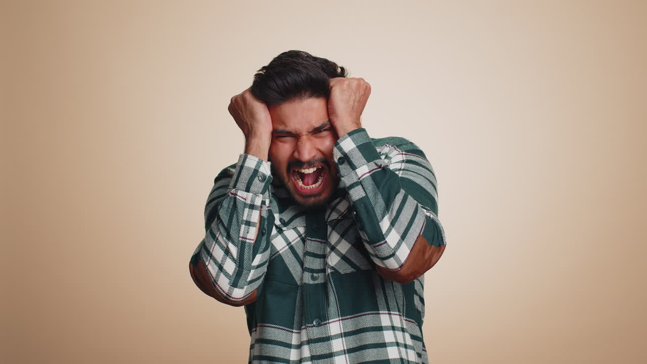 Indian man scared fearful covering ears with hands closing eyes meeting his own phobia freaked out