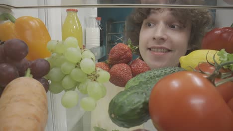 Person Eating Strawberries from Refrigerator