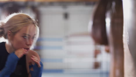boxeadora en entrenamiento de gimnasio con una bolsa de boxeo de cuero anticuada