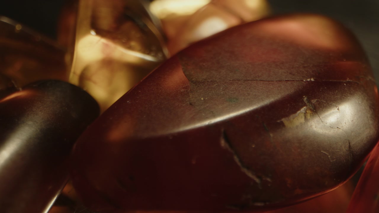 Bellissimo dolly macro di diverse gemme preistoriche di Burmite adagiate su una superficie metallica