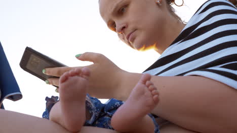 Woman-using-cellphone-while-baby-sleeping