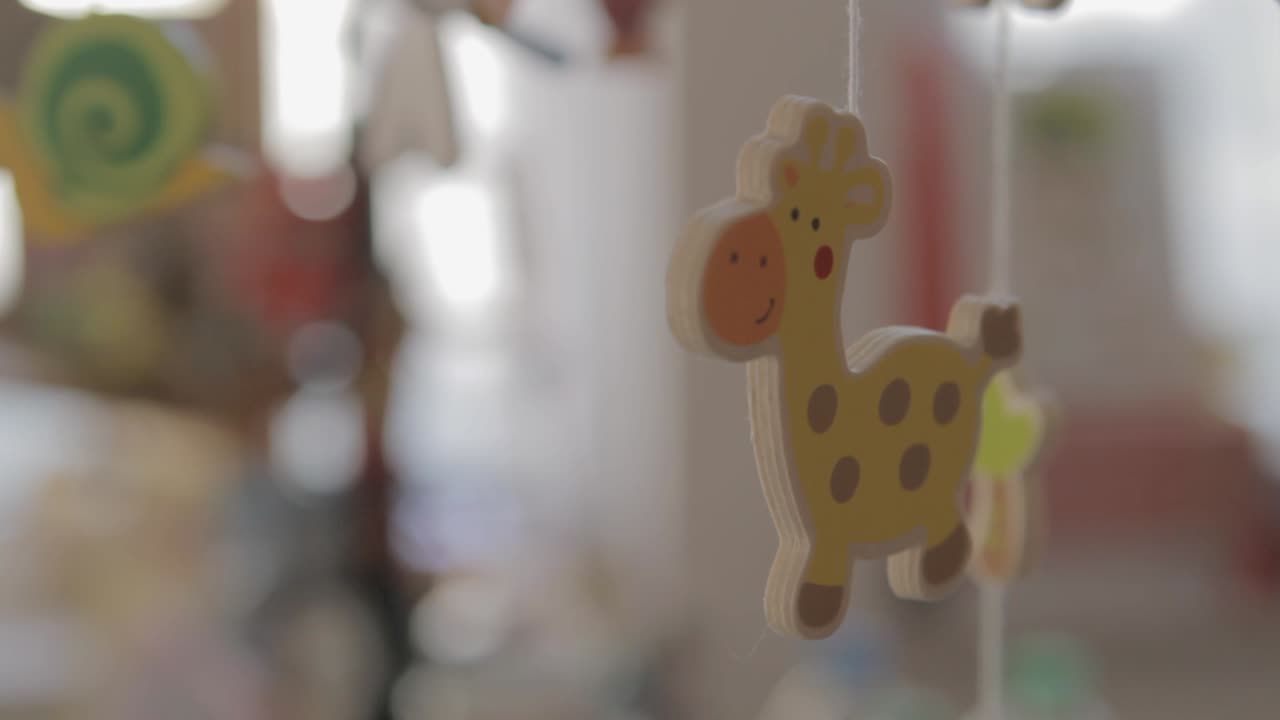 Blurry close-up of a colorful giraffe wooden mobile in a softly lit child's room