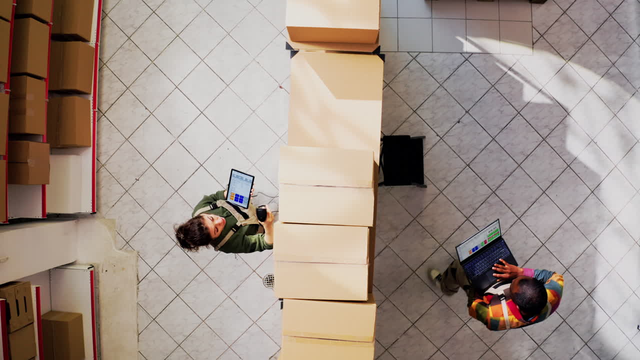 Warehouse workers checking inventory with laptops and tablets