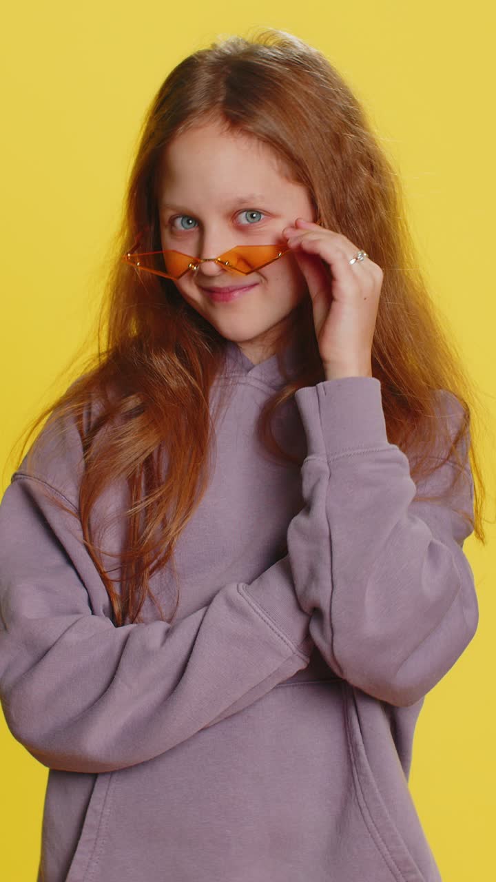 Child girl kid wearing orange sunglasses blinking eye looking at camera with smile winking flirting