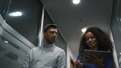 los gerentes del equipo trabajan en la tableta discutiendo el inicio del negocio en el pasillo de la oficina.