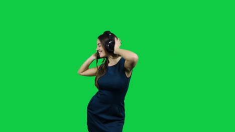 happy girl with headphones dancing in front of the green screen