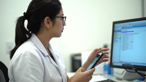 healthcare professional engaged with mobile communication while accessing digital information in a modern office setting