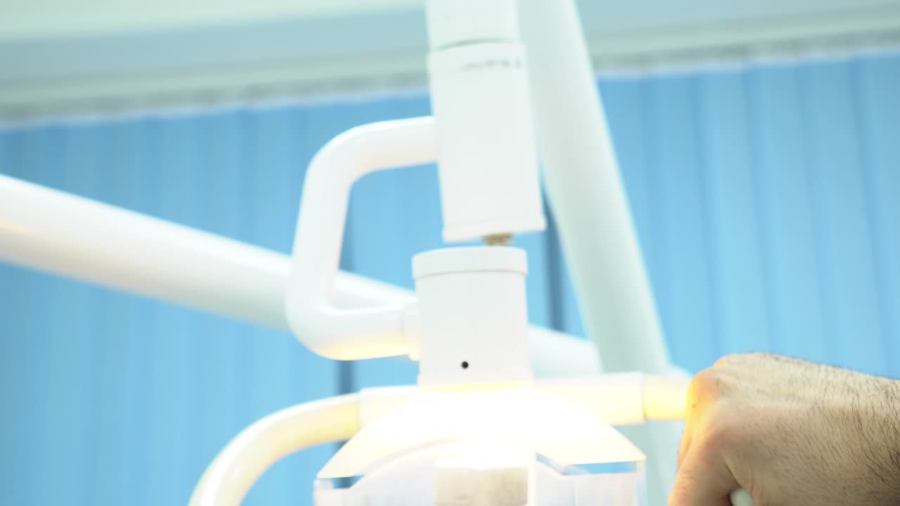 치과 의사가 치과 조명을 조정하고 있습니다.