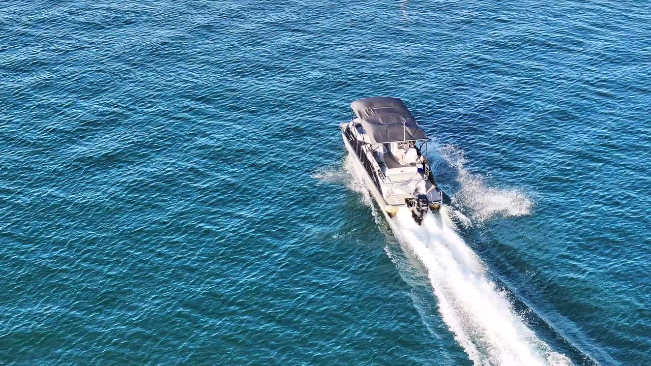 캘리포니아의 애로헤드 호수에서 큰 폰톤 보트가 파란 물에 큰 웨이크를 만들고 여름 시간 - 공중 트럭 팬을 따르십시오