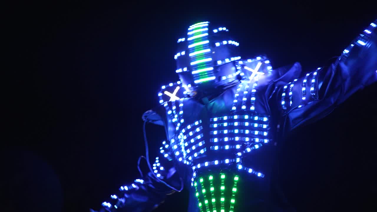 Performer in illuminated LED costume dancing at night in closeup