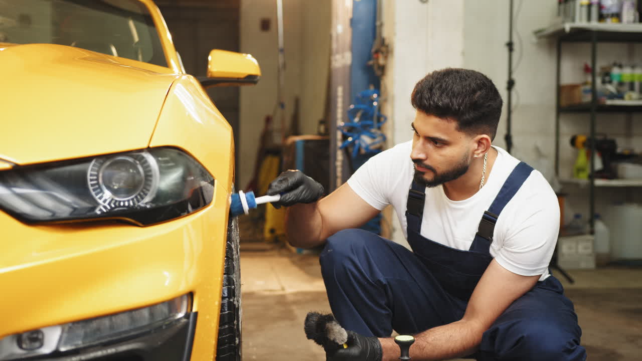 사람이 차고에서 노란색 스포츠카를 청소하고 있다