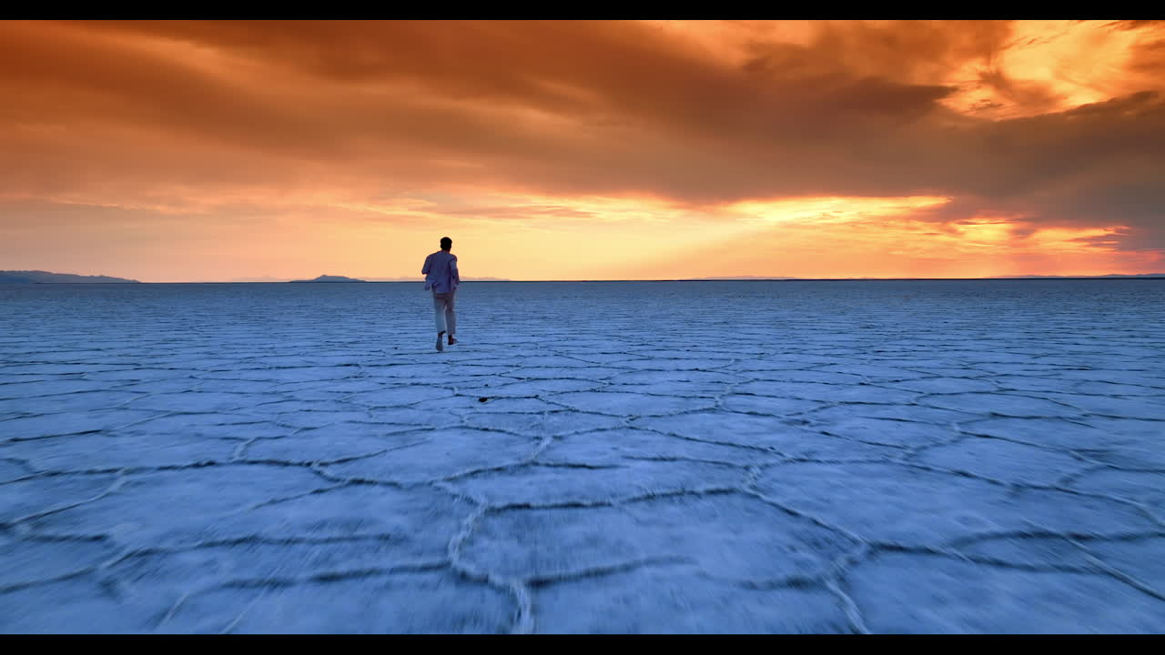 Following a man running by the salty landscape. Orange sky over the horizon. Bonneville Salt Flats, Utah, USA