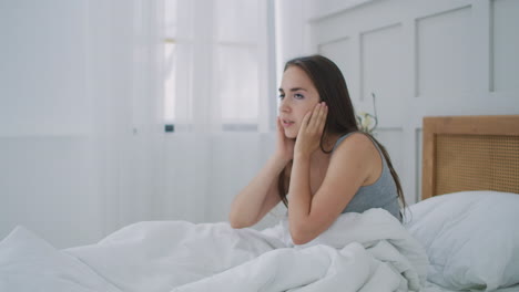 Woman-Waking-Up-With-Headache-In-Bed.-Sleepy-and-tired-young-girl-sitting-on-a-bed-struggling-with-headache