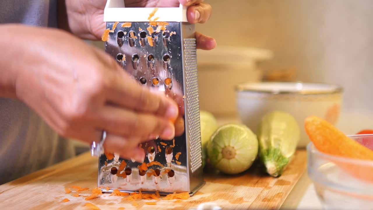 Close-up of hands grating carrots in a kitchen