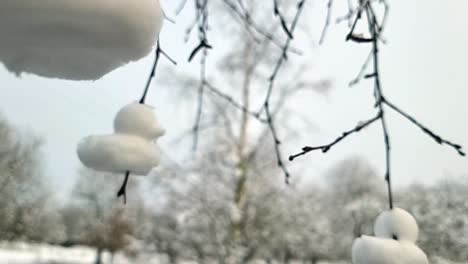 artistic shaped snow ducks decoration hanging from bare winter tree branches