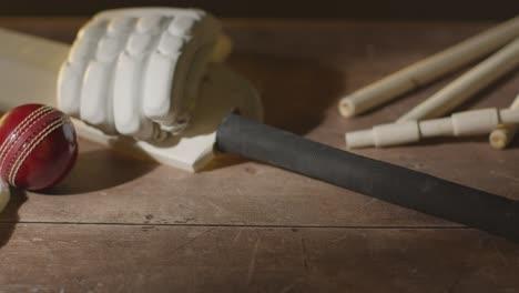 cricket-stillleben mit close-up-batball-handschuhe, stümpfe und bails, die auf einer holzoberfläche in der umkleidekabine liegen