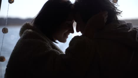 사랑에 빠진 젊은 커플이 호수 옆 캐러밴 뒤쪽에 머리를 맞대고 있습니다.