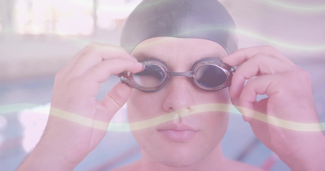 Nadador competitivo cogiendo gafas tintadas al borde de la piscina y colocándoselas en la cara para hacer ejercicio.