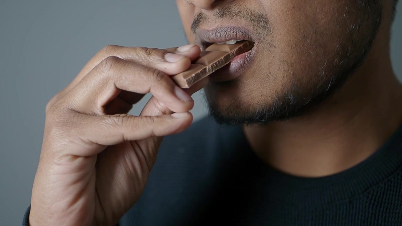 Nahaufnahme eines Mannes, der ein Stück Schokolade isst