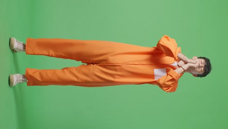 full body of asian male prisoner in handcuffs prays for something while standing on the green screen background