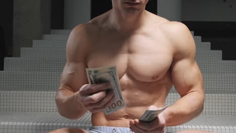 muscular athletic man counts money, dollar, throughs bills