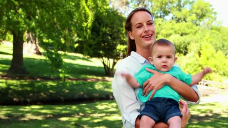 Madre-Feliz-Sosteniendo-A-Un-Lindo-Hijo-Sonriendo-A-La-Cámara