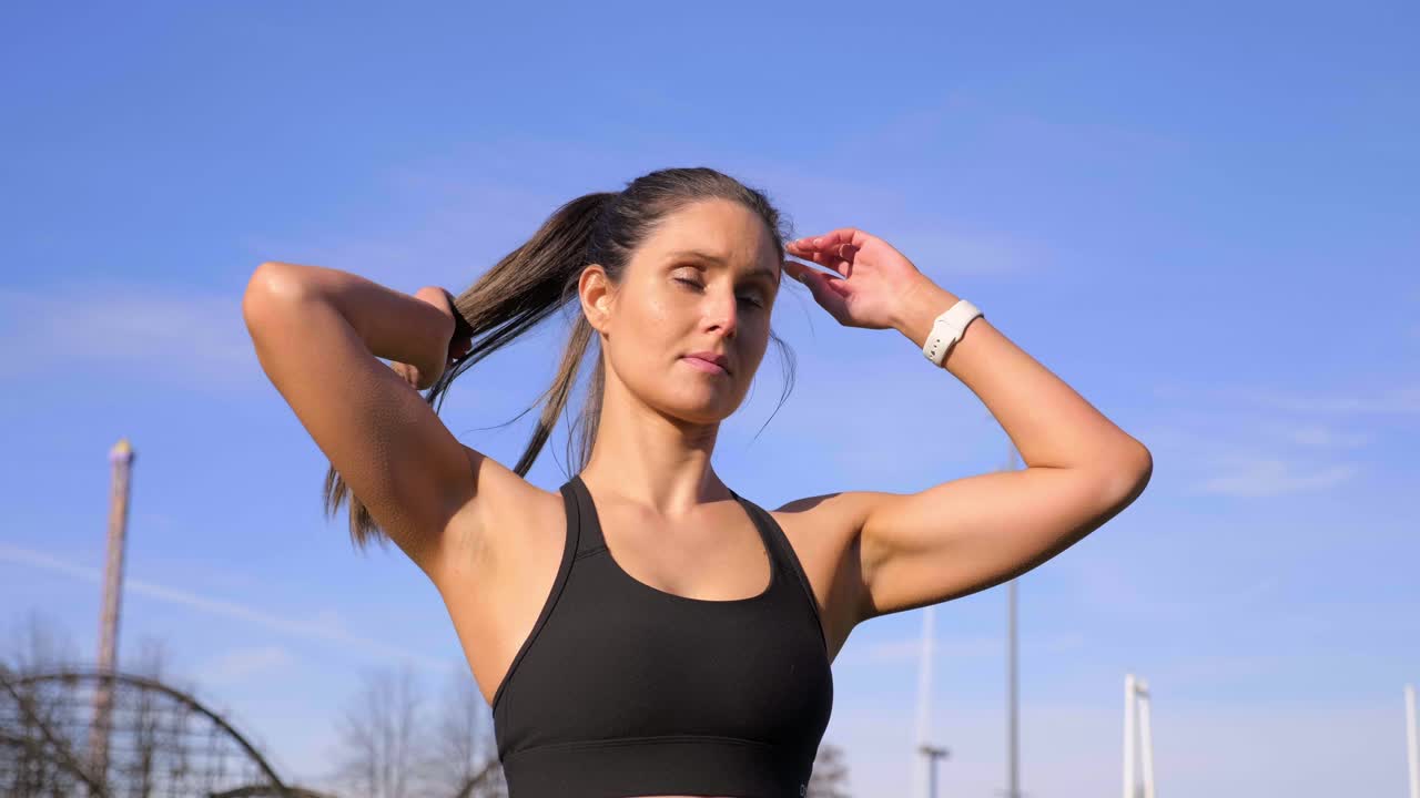 atractiva mujer atlética atando el cabello antes de correr a cámara lenta
