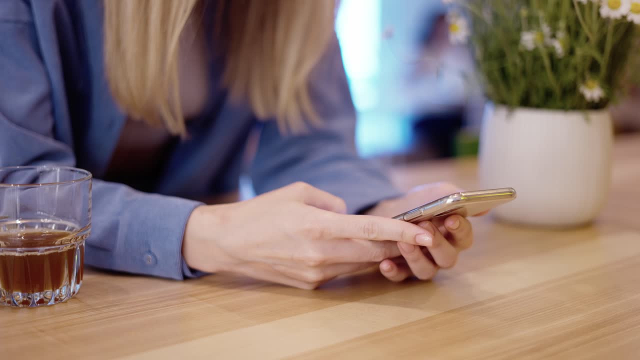 Unrecognizable woman hands using smartphone in a coffee shot